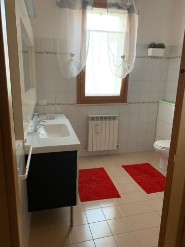 西尼加利亚TRA IL CENTRO E IL MARE的一间带水槽的浴室和一个带红色地毯的卫生间