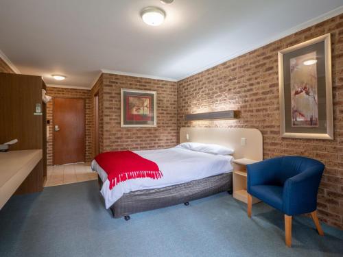 艾尔登Eildon Parkview Motor Inn Room 1的一间卧室配有一张床和一张蓝色椅子