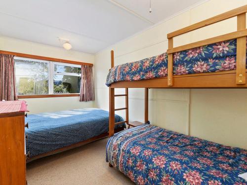 WaitahanuiLake Edge Cottage - Waitahanui Holiday Home的一间卧室配有两张双层床和一张床