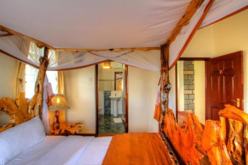 奈瓦沙Naivasha Kongoni Lodge - Lakefront Getaway的一间卧室设有天蓬床和一间浴室。