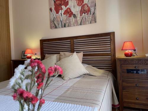 AdzanetaCasa con Encanto,disfruta de su paz y tranquilidad的一间卧室配有一张鲜花床和两盏灯。