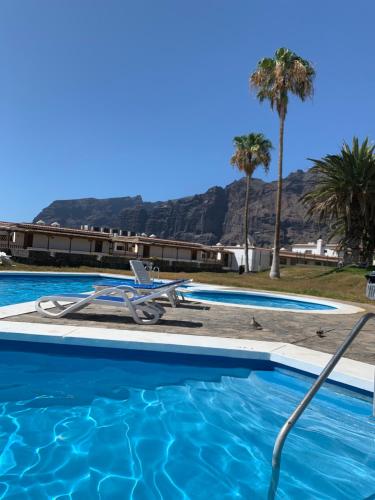 阿坎提拉德洛斯基Ocean View, Große Sonnenterrasse, Meerblick, Tamara Komplex, Teneriffa Süd, Los Gigantes, 500m Strand, Pool, 300m zum Ort, ruhig的一个带椅子和棕榈树的游泳池