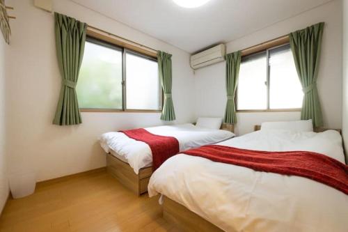 东京田端民泊ー田端ハウス的带2扇窗户的客房内的2张床