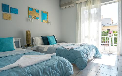 阿默达拉-伊拉克利翁RODI BLUE appartments的一间卧室配有两张带蓝色棉被的床和窗户。