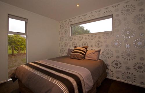 奥阿库尼Handbridge - Ohakune Holiday House的一间卧室设有一张床和两个窗户。