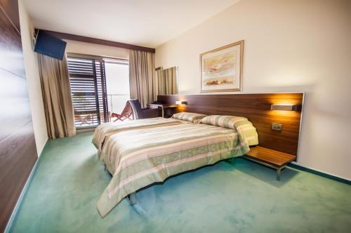 博扎瓦马克西姆酒店的配有一张床和一把椅子的酒店客房