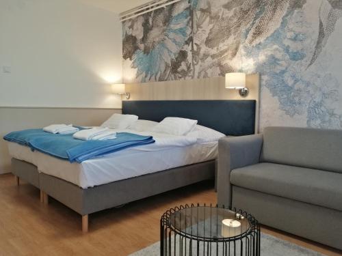 久洛赫福乐思酒店的一间卧室配有一张床、一张沙发和一把椅子
