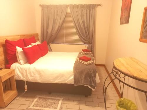 乌平通ChriZelo Self Catering unit的一间卧室配有一张带红色枕头的床和一扇窗户