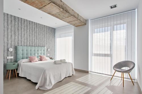 普拉森西亚9 NIDOS Céntrica Suites - Nuevo的一间卧室配有带粉红色枕头和椅子的床