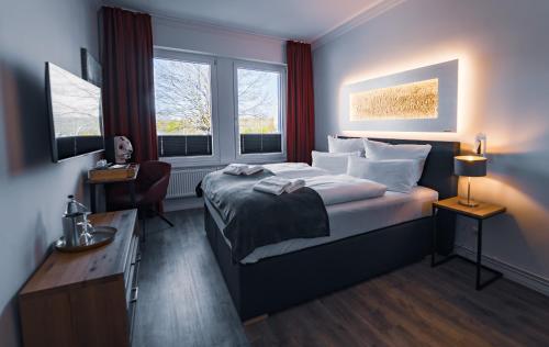 石勒苏益格Hotel Boutique am Schloss的一间卧室配有一张床、一张书桌和两个窗户。