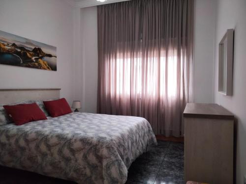 La GuanchaAPARTAMENTOS La PEÑA A的一间卧室配有一张带红色枕头的床和一扇窗户