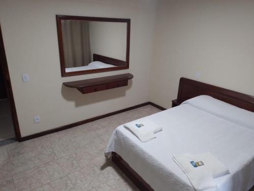 新弗里堡Hotel Recanto da Itália的卧室配有一张床,墙上设有镜子