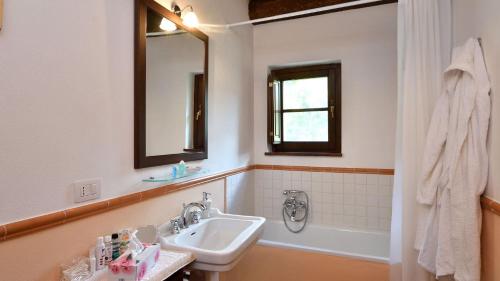 RoccalbegnaVilla Nocciola Il Poderone的浴室配有盥洗盆、镜子和浴缸