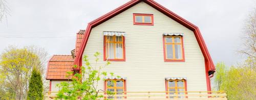 VikarbynHemma hos Jeanette & Micke på Peresgården的一间大型白色房屋,设有红色窗户