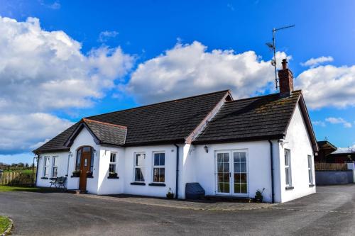 唐帕特里克The Heights & Hollows Farmhouse, Saul, Downpatrick, SLEEPS 14的黑色屋顶的白色房子