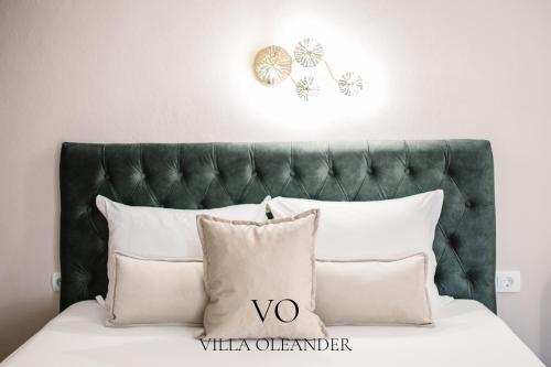 乌尔齐尼夹竹桃别墅公寓的一张带白色枕头和绿色床头板的床