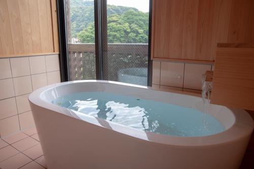 雾岛市雾岛美山酒店的带浴缸的浴室和窗户