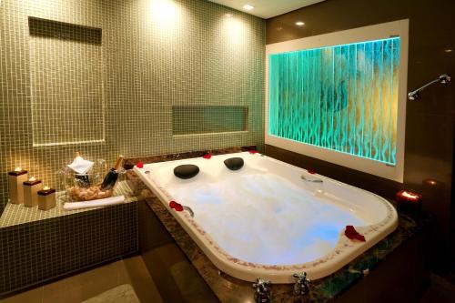 格拉玛多Sky Centro Hotel & SPA的带浴缸的浴室和大窗户