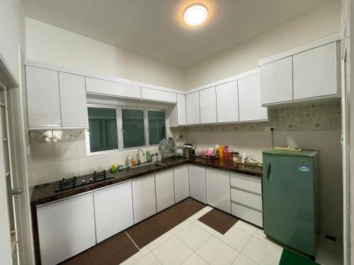 峇六拜NORISH HOMESTAY的厨房配有白色橱柜和绿色冰箱。