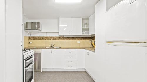 荷斯安山Alpine Heights 11B的白色的厨房配有白色橱柜和水槽