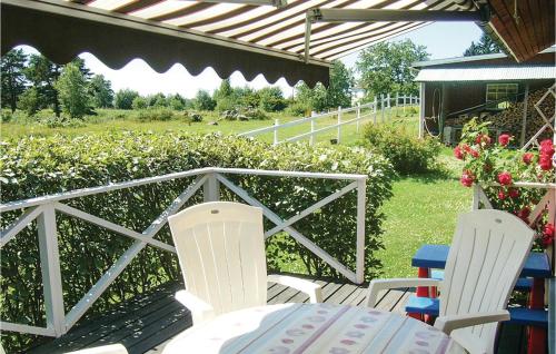 维默比2 Bedroom Amazing Home In Vimmerby的庭院设有两把椅子、一张桌子和围栏