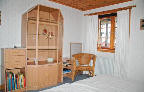 HäljebolNice Home In Uddevalla With 3 Bedrooms And Wifi的一间卧室配有木制橱柜、一张桌子和一把椅子