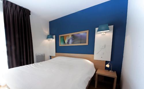 克莱蒙费朗厄斯德姆克莱蒙费朗日尔戈维亚酒店的一间卧室设有一张床和蓝色的墙壁