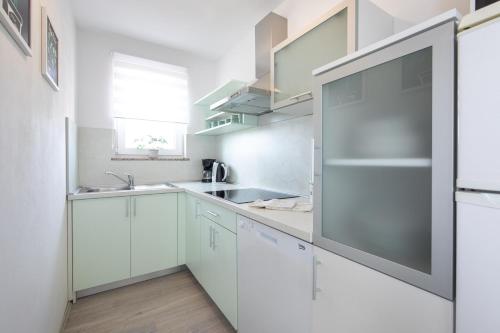 克尔克Apartment Kosic n1 beautiful & cosy的厨房配有白色橱柜和不锈钢冰箱