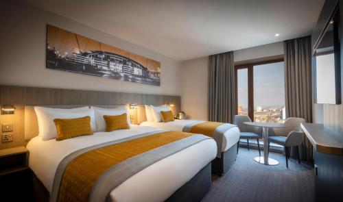 曼彻斯特Maldron Hotel Manchester City Centre的酒店客房配有两张床和一张书桌