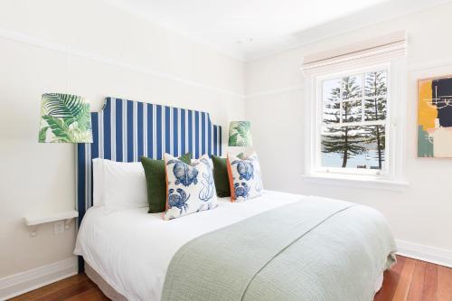 棕榈滩Barrenjoey House的白色卧室配有一张带蓝色和白色枕头的大床