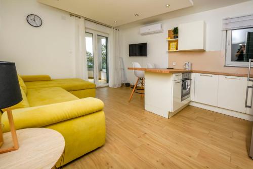 罗戈兹尼察Apartments Seaside apartments Polic的一间带黄色沙发的客厅和一间厨房