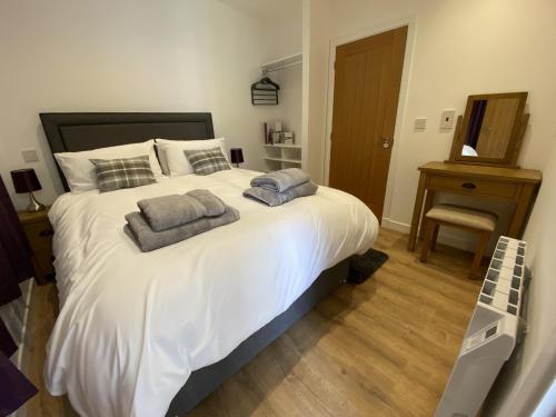 德里门White Cottage - Cosy Holiday Cottage in Drymen, Loch Lomond & Trossachs的卧室配有一张带两个枕头的大白色床