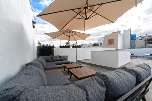 因赫尼奥CASA VERDE Comfortable Air-Conditioned Modern Apartments的天井配有沙发、桌子和雨伞。