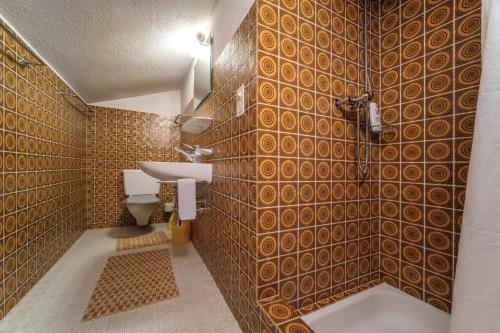 阿罗萨Casa Dschember, Wohnung 11, 1-6 Personen的浴室设有棕色瓷砖墙和水槽