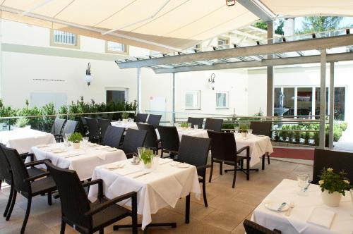 布雷根茨韦碧斯克鲁兹酒店的餐厅设有白色的桌椅和窗户。