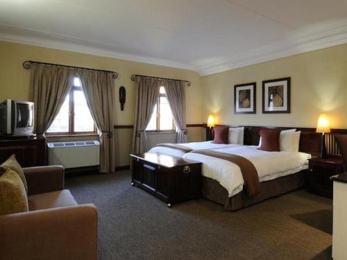 哈博罗内皮蒙特莫迪尔酒店的一间卧室设有一张大床和两个窗户。