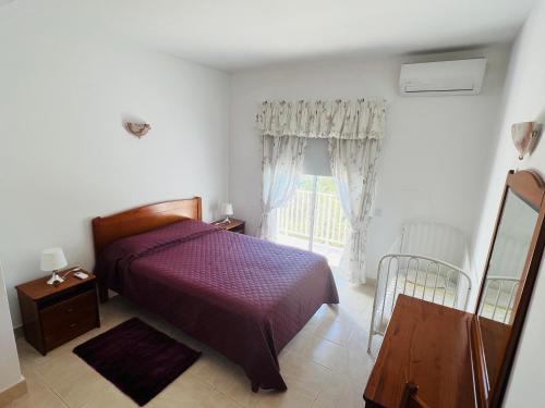 圣巴巴拉-迪内希Vila Flora的一间卧室设有紫色的床和窗户
