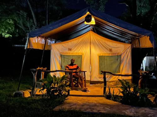 MorotoKara-Tunga Safari Camp的男人在晚上坐在帐篷里
