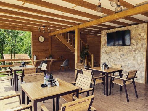 BozioruTinutul Luanei Glamping Resort的餐厅设有木桌、椅子和电视。