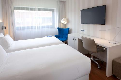马德里马德里本塔斯NH酒店的酒店客房设有两张床、一张桌子和一台电视。