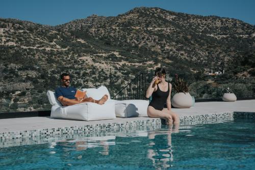 依拉佩特拉Pignolia Suites - Adults Only的坐在游泳池旁沙发上的男女