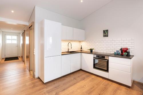 雷克雅未克Lundur Apartments的厨房铺有木地板,配有白色橱柜。