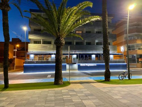 圣佩德罗-德尔皮纳塔尔海王星酒店的一座在晚上有棕榈树的建筑