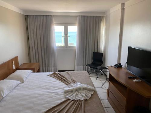 纳塔尔Ponta Negra Flat ByHotéis的一间卧室配有一张床、一张书桌和一台电视