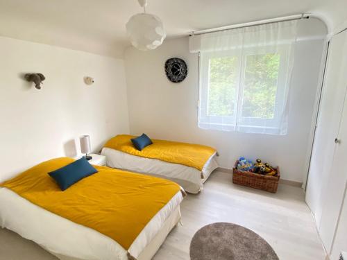 勒帕莱Le coteau的一间卧室设有两张带黄床单的床和窗户。