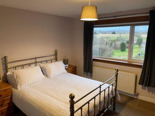 邓迪Baldovan Cottage的一间卧室设有一张床和一个大窗户