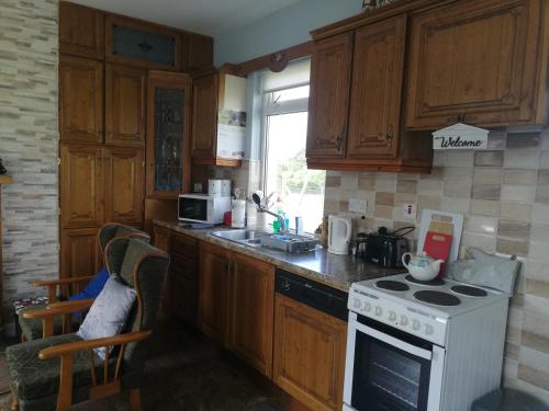 巴利纳Rossport bungalow with an Atlantic view的厨房配有木制橱柜和白色炉灶烤箱。
