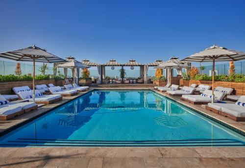 洛杉矶60比佛利山酒店的一个带躺椅和遮阳伞的游泳池
