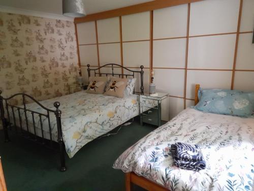 柯克宾Grovewood House Retreat的一间卧室配有两张床,还有一个床头柜和床架