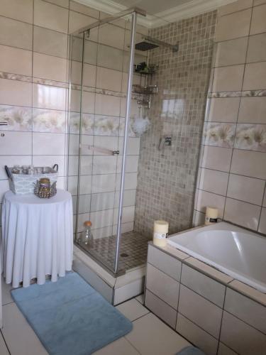 BrakpanCheerful Family Holiday Home的带淋浴和浴缸的浴室以及桌子。